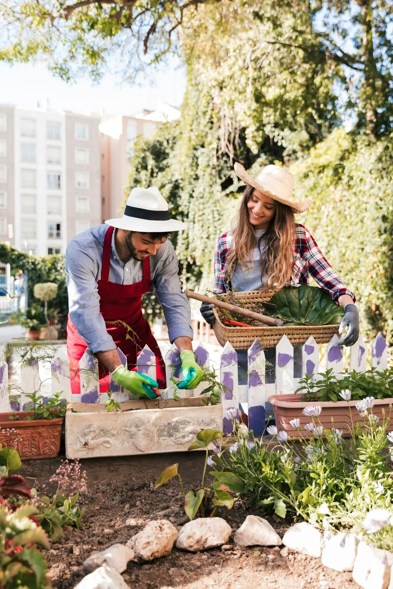 A portrait featuring a smiling male and female gardener working in the garden.